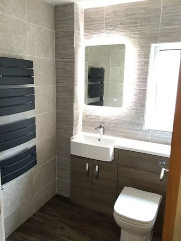 Bathroom with a wall-hung basin unit, backlit mirror and heated towel rail