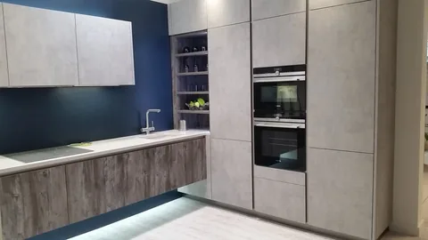 Kitchen with concrete-effect tall units, built-in ovens and a navy wall